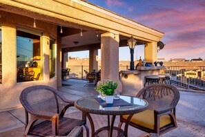An outdoor patio with wicker chairs, a glass table, and a potted plant.