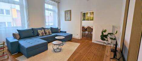 A modern living room with a sectional sofa, a small round table, and a radiator.