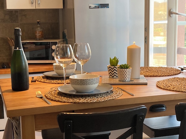 A dining table set with plates, bowls, wine glasses, a candle, and a bottle. - Charming apartment Urrugne côte basque (Urrugne)