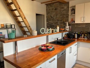 A kitchen with a wooden countertop, a stone wall, a sink, and a staircase. - Charming apartment Urrugne côte basque (Urrugne)