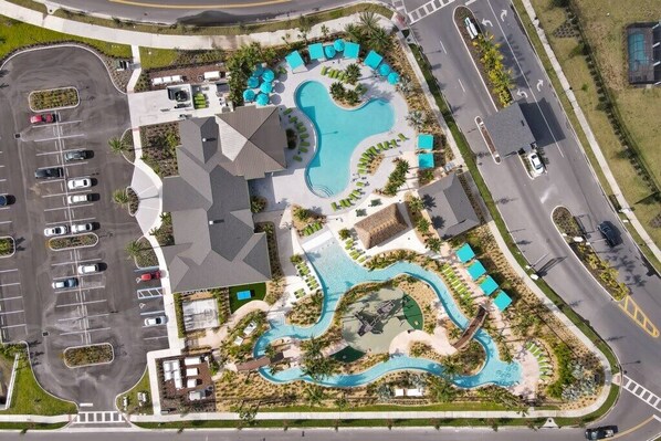 Luftaufnahme eines Resorts mit Schwimmbad, Liegebereichen und Parkplatz.