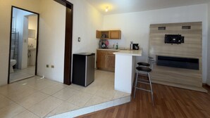 A compact kitchen with a refrigerator, sink, and bar stools.