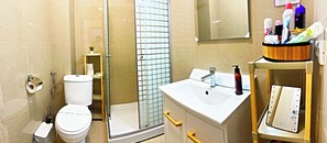 Une salle de bain comprenant des toilettes, une douche, un lavabo et un miroir.