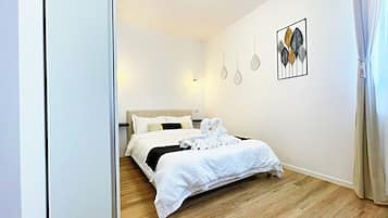 Un dormitorio con cama, suelo de madera y una obra de arte en la pared.