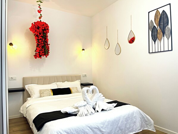 Une chambre d’hôtel avec un lit, un arrangement floral fixé au mur et une œuvre d’art décorative.