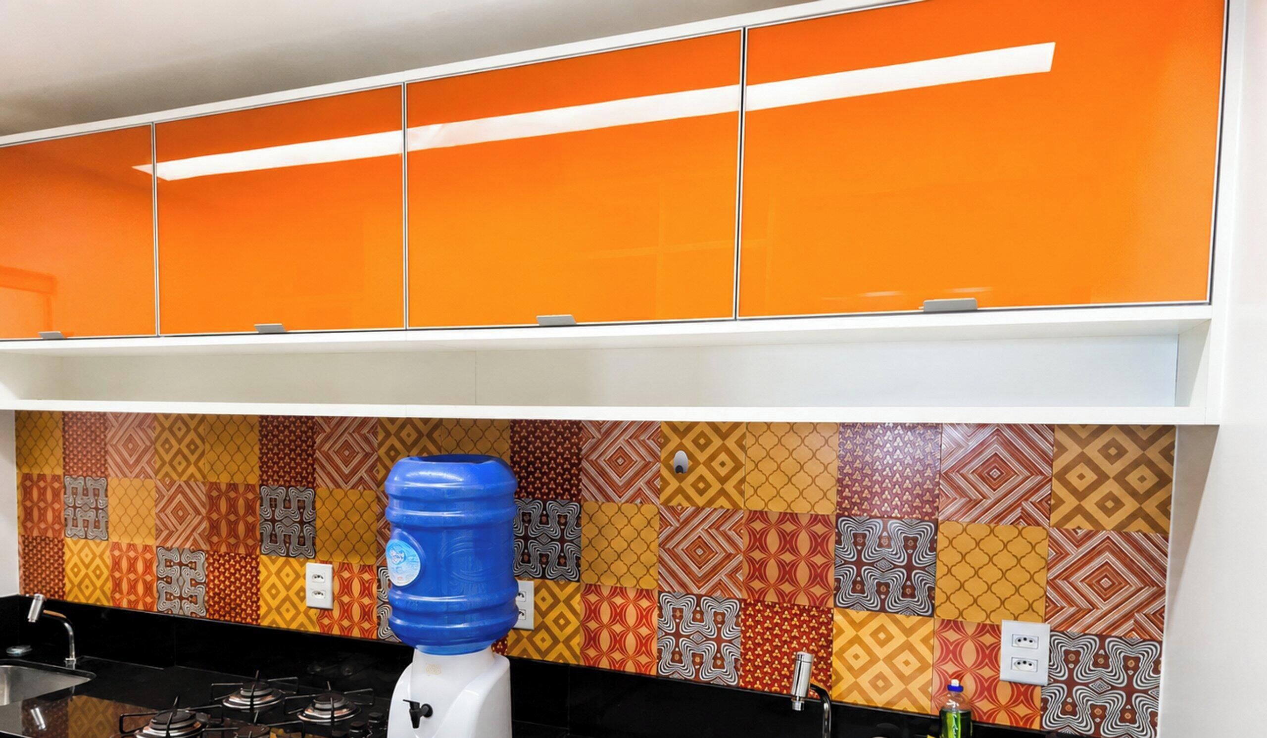 Uma cozinha com armários laranjas, um painel de fundo estampado, um dispensador de água azul e um fogão a gás.