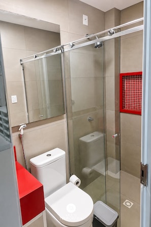 A modern bathroom with a glass-enclosed shower, a toilet, and a red accent wall.