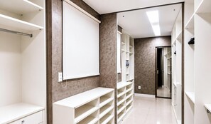 A walk-in closet with open shelving, a whiteboard, and a mirror. - Studio no Coração da Cidade Velha - PA (Belém)