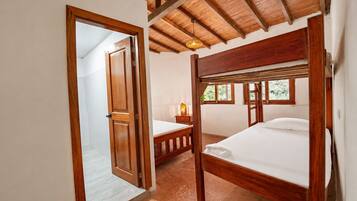 A bedroom with two wooden beds, a nightstand, a lamp, and a window with a view.