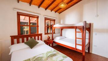A room with a bunk bed, a single bed, a small bedside table, and a window with a view.