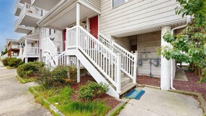 A row of two-story townhouses with front porches, a red door, and a white staircase. - Spacious coastal townhouse with multiple decks, gas fireplace, & relaxing Bay views (Ocean City)