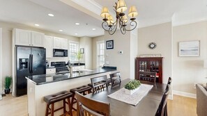A modern kitchen with a central island, built-in appliances, and a dining area with a chandelier. - Spacious coastal townhouse with multiple decks, gas fireplace, & relaxing Bay views (Ocean City)