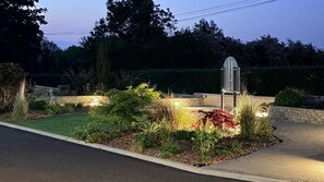 Un jardín ajardinado con un sendero, una pequeña fuente de agua y una escultura de metal.
