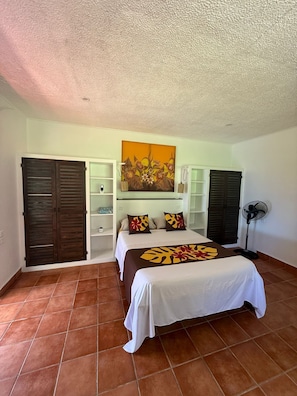 Un dormitorio con cama, un cuadro, un ventilador y un armario.