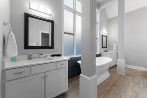 Ein modernes Badezimmer mit einem großen Spiegel, einer Badewanne und einem Waschtisch.