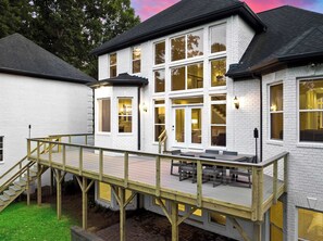 Un bâtiment à deux étages doté d’une terrasse, de grandes fenêtres et d’un escalier.