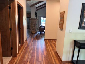 A hallway with wooden flooring, a stone pillar, a wicker basket, and a black table.