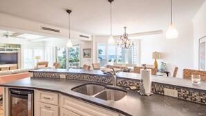 A kitchen with a large island, double sink, and modern pendant lighting.