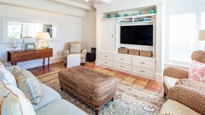 A living room with a sofa, ottoman, TV, and storage unit.