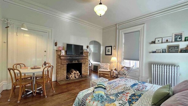 Ein Schlafzimmer mit Kamin, einem Bett mit floraler Steppdecke, einem Schreibtisch mit Stuhl und einem Fernseher.