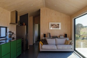 A modern kitchen with green cabinets, a built-in stove, and a large window.
