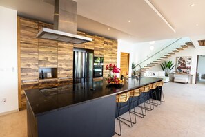 Eine moderne Küche mit Kochinsel, Edelstahlgeräten und einer Wand in Holzoptik.