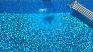A clear blue pool with a tiled edge and a metal ladder.