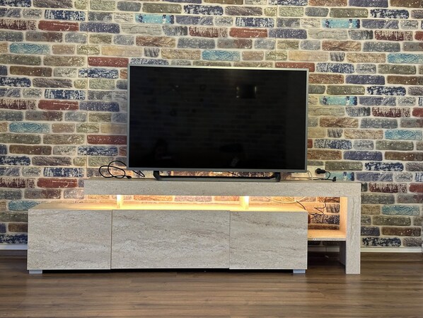 A flat-screen TV on a light-colored console against a brick wall. - Villa with Private Pool Near the Sea (Aydın)