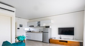 Eine moderne Küche mit weißen Schränken, einem Edelstahlkühlschrank, einer Mikrowelle und einem eingebauten Fernseher.