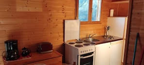 A compact kitchen with a stove, sink, and a coffee maker. - Chalet Brumalis - MALZIEU VILLE (LE) (MALZIEU VILLE (LE))