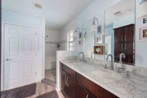 Un baño con lavamanos doble, armarios de madera oscura, un espejo grande y pared de azul claro.