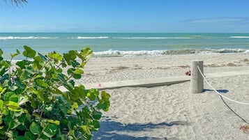 Une plage avec une clôture en bois, une corde attachée à un poteau et une vue dégagée sur l’océan.