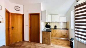 Una cocina con armarios de madera, encimera negra y ventana con persianas.