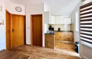 Eine Küche mit Holzschränken, einer schwarzen Arbeitsplatte und einem Fenster mit Jalousien.