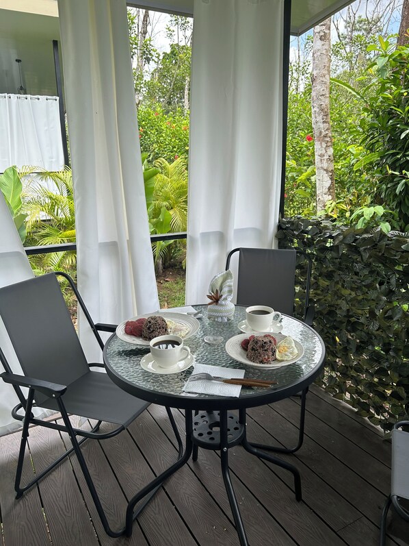 A round glass table with four chairs, a white tablecloth, and a glass coffee cup. - 🌿 Private Getaway in La Fortuna -Bungalows Jacuzzi, River and Nature ✨ 20 min. (Fortuna)