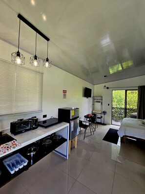A modern kitchen with a built-in oven, a refrigerator, and a dining area with a table and chairs. - 🌿 Private Getaway in La Fortuna -Bungalows Jacuzzi, River and Nature ✨ 20 min. (Fortuna)