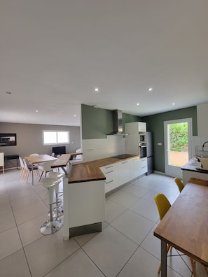 A modern kitchen with white cabinets, a wooden countertop, and a built-in oven. - 🌿 Villa L'Olivier Private pool, garden, 8 people, air conditioning and beaches 4 km away 🌊 (Portiragnes)