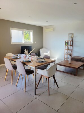 A dining area with a wooden table, chairs, and a television. - 🌿 Villa L'Olivier Private pool, garden, 8 people, air conditioning and beaches 4 km away 🌊 (Portiragnes)