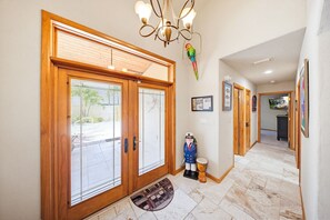 A hallway with wooden doors, a bird sculpture, a nutcracker, and a tiled floor. - Waterfront Pool Home w/ Private Dock, Tiki Hut & Backyard Oasis (Marathon)