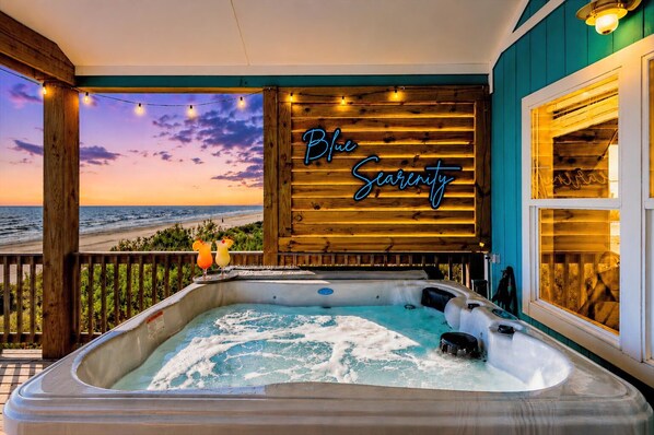A hot tub on a balcony with a view of the beach and a neon sign reading 'Blue Serenity.' - Beachfront Hot Tub overlooking gulf, Bar & Games, Pet-Friendly (Gilchrist,)