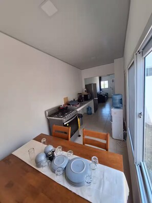 A modern kitchen with a dining area, featuring a stove, refrigerator, and water dispenser. - Contemporary House with Pool Access (Sitio del Niño)