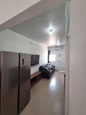 A modern living room with a flat-screen TV, a sofa, and a built-in refrigerator. - Contemporary House with Pool Access (Sitio del Niño)