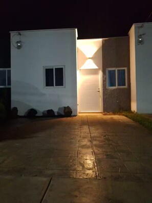 A building with a paved entrance, a lit door, and a small window. - Contemporary House with Pool Access (Sitio del Niño)