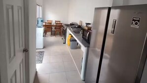 A kitchen with a refrigerator, a water dispenser, and a dining area with chairs and a table.