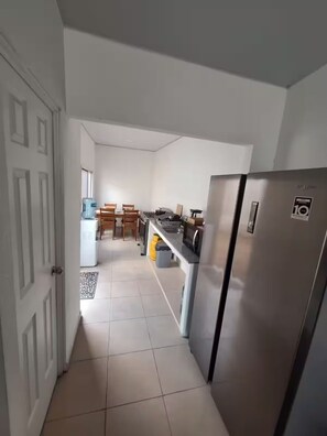 Una cocina con refrigerador, dispensador de agua y comedor con sillas y mesa.