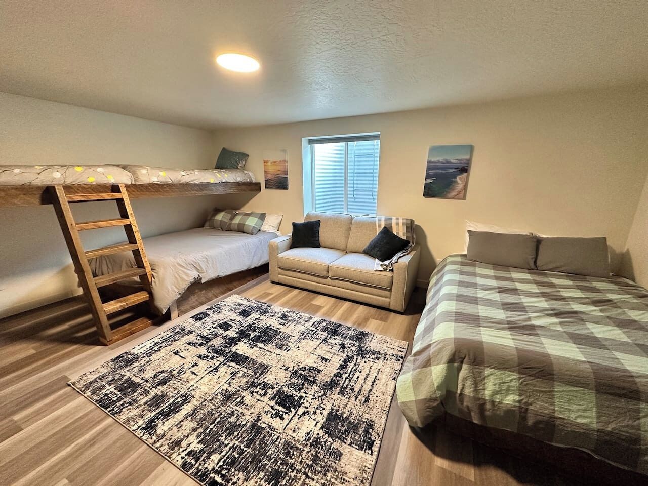 A bedroom with bunk beds, a sofa, a window, and a rug.