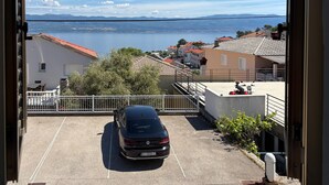 Un espace de stationnement avec une voiture, une vue sur un lac et des bâtiments aux toits recouverts de tuiles rouges.