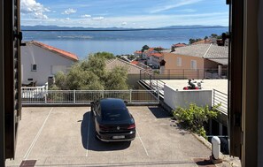Ein Parkplatz mit einem Auto, Blick auf einen See und Gebäuden mit roten Ziegeldächern.