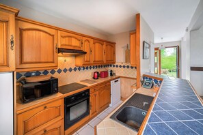 Une cuisine avec des meubles de rangement en bois, un four à micro-ondes, un four traditionnel et un lave-vaisselle.