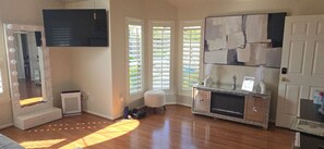 A room with a vanity mirror, a flat-screen TV, a cabinet, and a window with blinds. - Beautiful 3-bedroom house w/AC in charming Cypress/Houston area. (Cypress)
